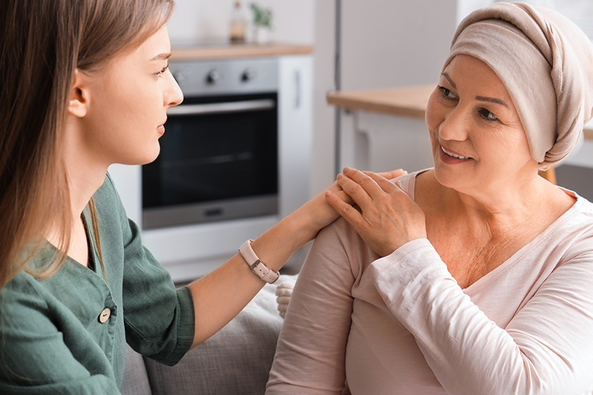 Mature woman after chemotherapy with her daughter holding hands at home, closeup. Stomach cancer concept 