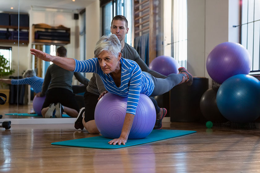 Physiotherapist assisting senior woman in performing exercise