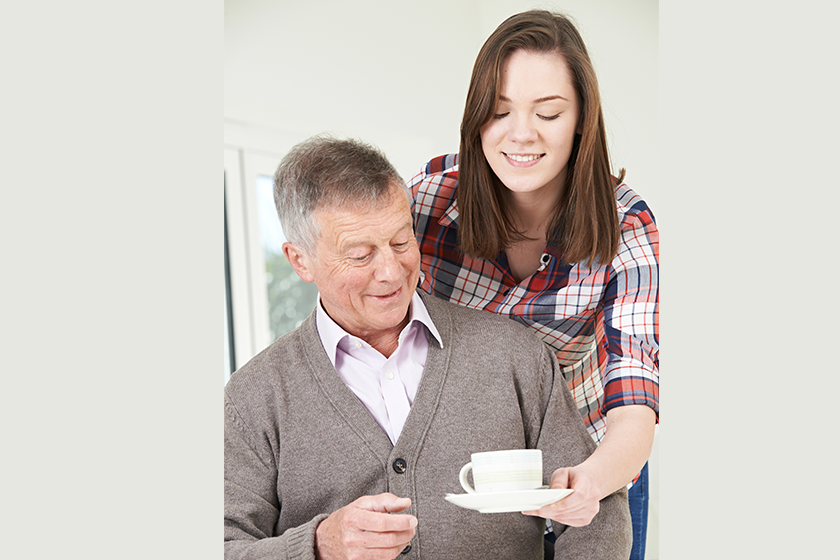 Teenage Granddaughter Bringing Grandfather Hot Drink 